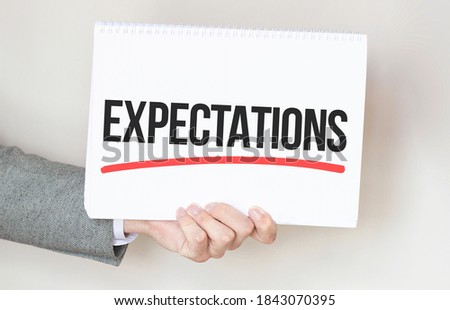 businessman holding a card with text EXPECTATIONS