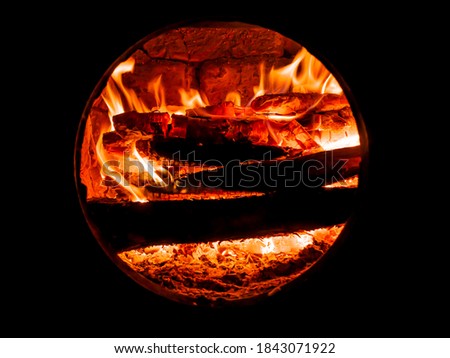 Red flame of fire in a wood stove. Fire sparks. Bright flame of a bonfire in the night. Fiery sparks above the wood. Fiery smoke. Heat in the furnace. Background image. Firefighter. Danger of arson.
