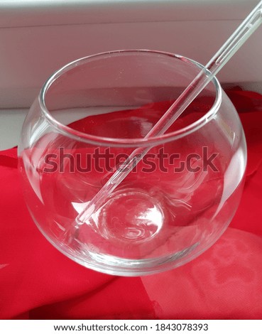 Round transparent vase with a cocktail stick, on a red cloth.
