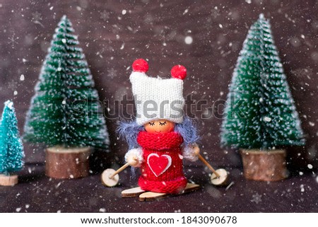 Winter composition Girl skiing 
in red clothes and white hat, Christmas tree on wooden background Xmas Holiday card Merry Christmas concept 
