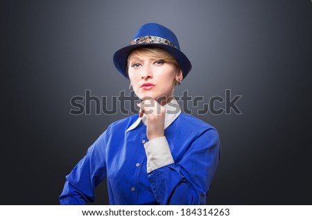 Portrait of an serious woman in a blue hat, dark background