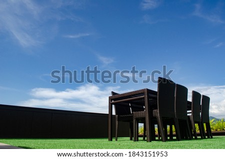Rattan table and chair set outdoor on green grass and blue sky background. it's using for business meeting and relax time
