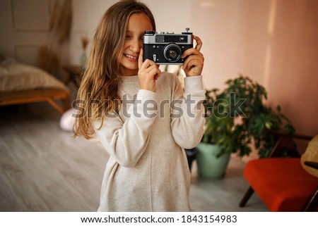 Cute Little Happy Girl With Vintage Photo Camera in a bright room