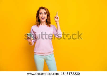 Excellent Photo of pretty lady hold telephone hands have creative post idea raise finger intelligent person wear pink pullover green pants isolated yellow color background