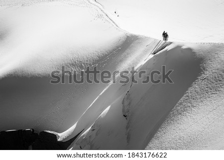 Trekkers hiking up a snowy ridge on White Valley, Mont Blanc massif from Aiguille du Midi 3842m, Chamonix, France