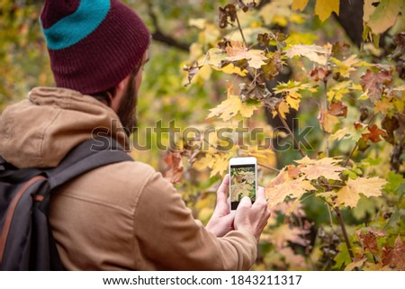 man taking picture in the autumn park. Surrounded by trees in the forest.