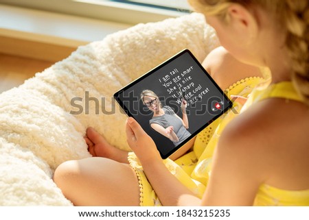 Girl learning English at home via video call on digital tablet
