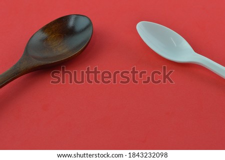 Wooden spoon and white spoon isolated on a red background. Food and drink concept. Copy space for text.