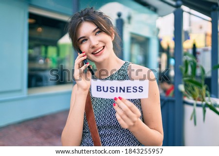 Young caucasian businesswoman talking on the smartphone and holding business word paper at the city.