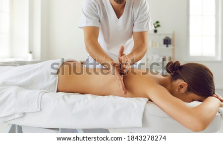 Relieving back muscle tension. Male masseur massaging young woman using Tapotement movements aka chopping, tapping or hacking technique during Swedish massage therapy in spa salon or wellness center Royalty-Free Stock Photo #1843278274