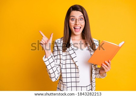 Photo of beautiful attractive amazed student dressed plaid jacket pointing finger empty space open copybook arm isolated yellow color background