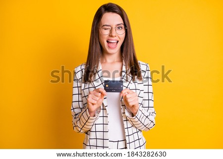 Photo portrait of attractive female company worker showing credit card winking blinking isolated on vivid yellow color background