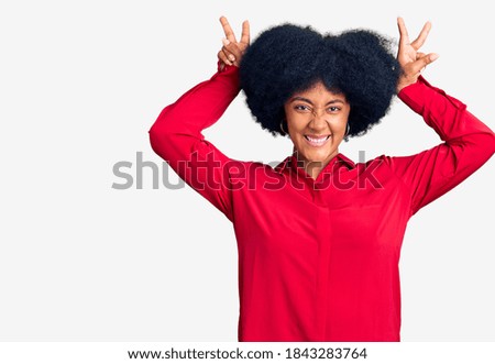 Young african american girl wearing casual clothes posing funny and crazy with fingers on head as bunny ears, smiling cheerful 