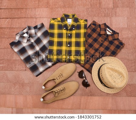 men’s mockup with checkered tartan plaid shirt,  and brown shoes with sunglasses, hat on wooden background

