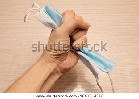 medical disposable mask for protection against carpet crumpled with force in the left hand in the fist 