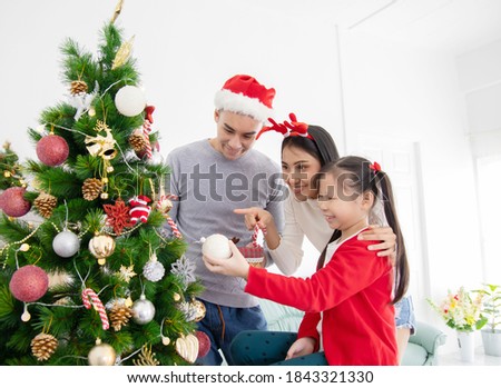 Happy family decorating a Christmas tree with baubles at home