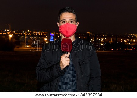 Reporter man wearing red mask giving the evening news. Journalism concept Royalty-Free Stock Photo #1843357534