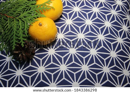 Tangerines and a green juniper branch on a blue background with snowflakes