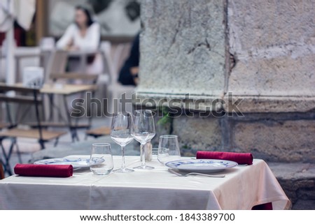 Empty outdoor restaurant table for two. Summer terrace cafe. Blurred background.