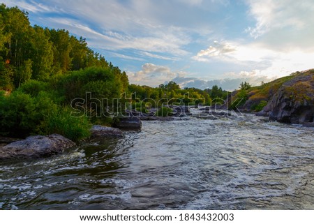 swirling streams of mountain river with rocky shore in a beautiful valley in forest, top view.