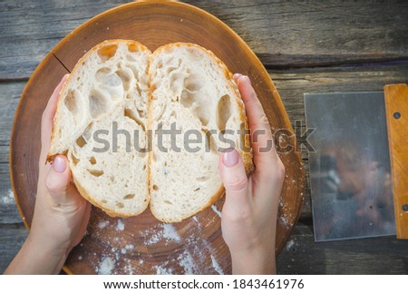 Baker woman holding homemade rustic wheat bread in hands. Selective focus.