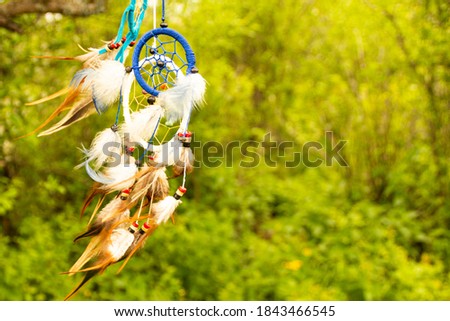 Dreamcatcher at sunset with copy space, symbol, tradition, signs. boho stylDream catchers evolve in the wind, against a blurred green background of plants with copy space, symbol, tradition, signs