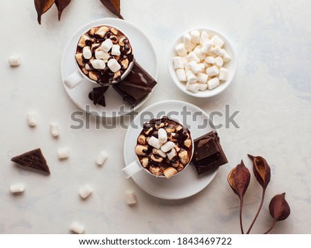 Cups of hot chocolate on white background with marshmallows and chocolate pieces. Top view.