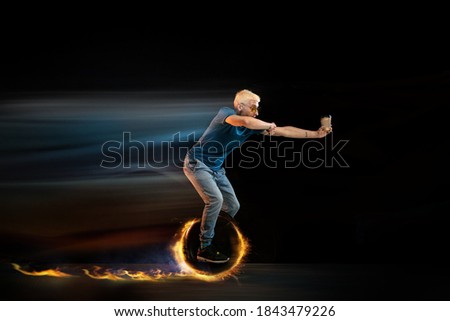 Coffee break. Fast delivery service - deliveryman on unicycle driving with order in fire on dark background. Copyspace for ad. Super fast shipping of food and goods orders during quarantine.