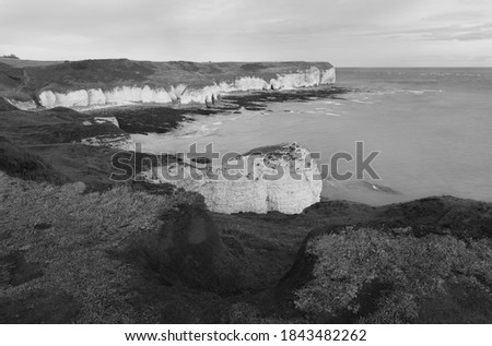 Sunrise over sea and eroded chalk cliffs under bright autumnal sky at low tide along north east coastline along Flamborough Head in East Riding of Yorkshire, UK.