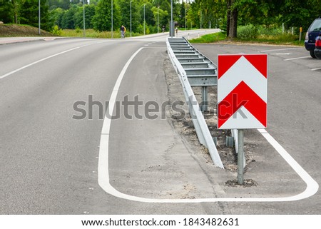 a metal safety barrier with a red and white striped traffic sign