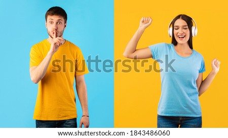 Man gesturing hush sign with finger on lips, keep silent, happy woman listening to music wearing wireless headphones and dancing, enjoying sound, isolated on blue and yellow studio background wall
