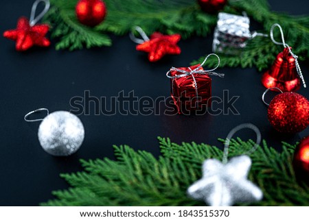 Christmas composition with red gift. Fir tree, gift and toys. Winter holiday theme. Space for text. Blurred focus background. 