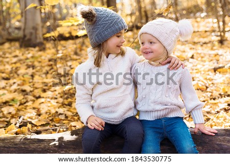 cute caucasian kids on fall season outdoors sit on log