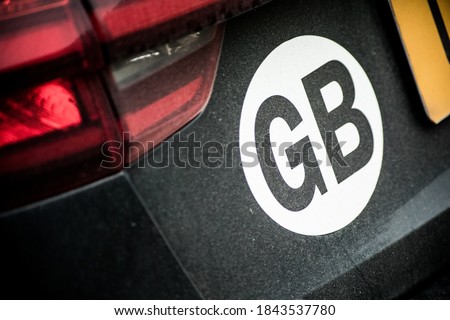 A close up shot of a GB country designation sticker on the rear of a black car. Nice clear focus on the sticker, car is slightly dirty, with the numberplate creeping into the frame. Royalty-Free Stock Photo #1843537780