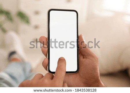 Man using mobile phone with empty screen indoors, closeup