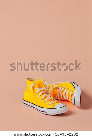 Yellow canvas sport shoes on peach background