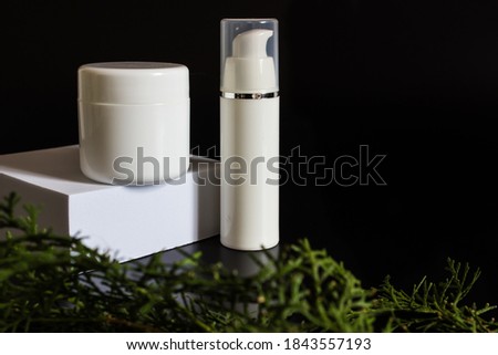 white rectangular box with shadows on a black background. White plastic cream jar. For cosmetics or cosmetology background. stand for advertising beauty products. Plants decor eucalyptus, fern, spruce