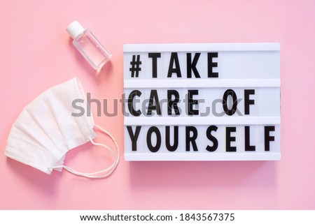 Lightbox with words Take Care of Yourself on pink background. With disinfectant and mask. 