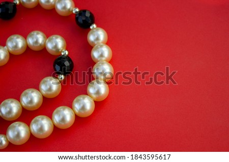 Old vintage necklace with pearl laying isolated on red background,fashion flat lay with retro bijouterie,print as postcard for mothers and womens day,greeting card,free place for text,copy space