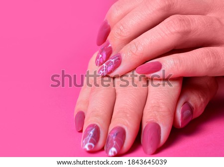 female hands with painted nailson on pink background. copy space.