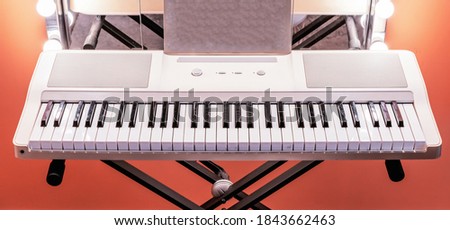 White digital piano or electronic synthesizer on a black metal stand.
