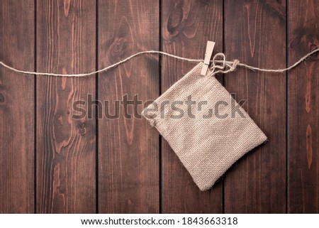 cloth bag and clothespin on a rope above a wooden dark background, top view, copy space