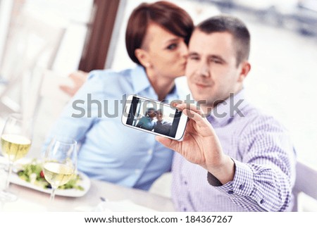 A picture of a young couple taking a picture in a restaurant