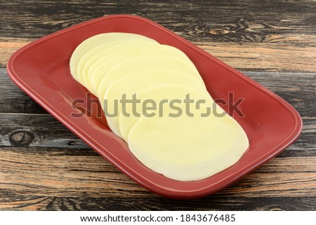 Provolone cold cut cheese slices on red serving platter on table Royalty-Free Stock Photo #1843676485