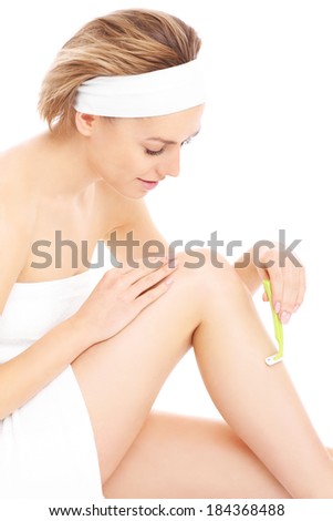 A picture of a young woman shaving her legs over white background