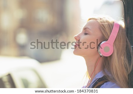 Young woman listening music in headphones in the city Royalty-Free Stock Photo #184370831