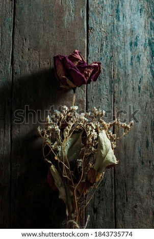 The dried roses are in a dry bouquet on a rustic wooden background.