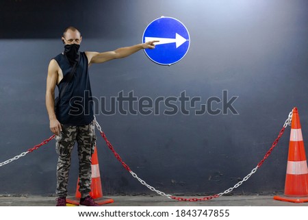 The hand points to the blue sign with arrow, round blue sign with arrow, pointing to the right.