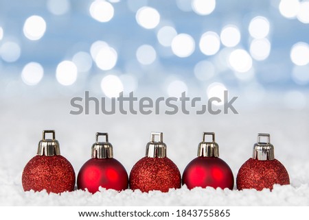 Christmas baubles on snow with bokeh lights