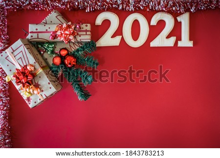 Group of Christmas presents with ribbon and bows,  2021 in wooden letters and ornaments on a red background. Copy space